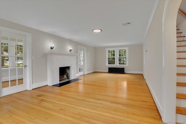 502 Adams St, Manchester, CT 06040 - unfurnished living room with radiator heating unit, stairway, light wood-type flooring, ornamental molding, and a fireplace with flush hearth