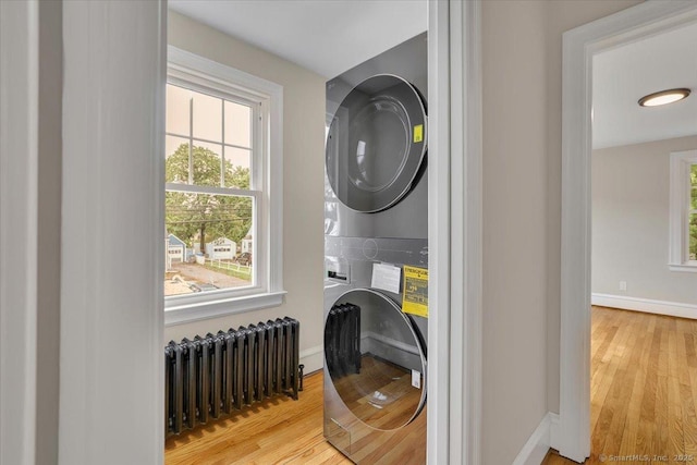 502 Adams St, Manchester, CT 06040 - washroom with stacked washer / drying machine, radiator heating unit, wood finished floors, and plenty of natural light