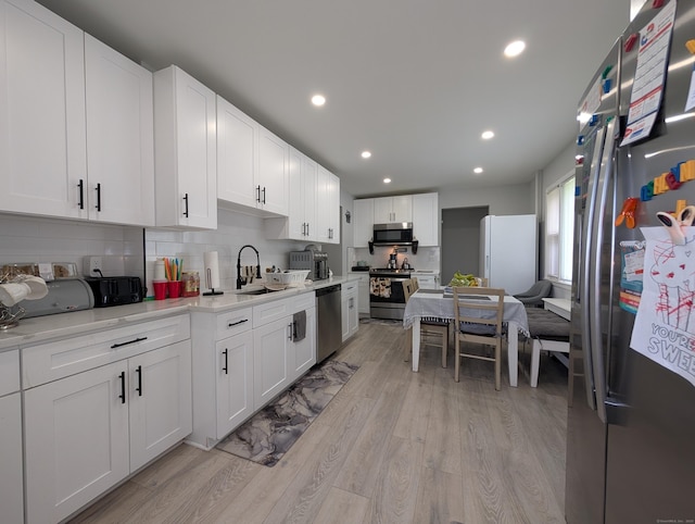 18 Victory St, Bridgeport, CT 06606 - kitchen featuring appliances with stainless steel finishes, decorative backsplash, light countertops, light wood-style flooring, and recessed lighting