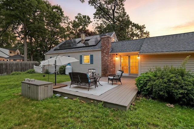 17 Wilstar Cir, Enfield, CT 06082 - back of property with roof mounted solar panels, an outdoor living space, a deck, roof with shingles, and a chimney