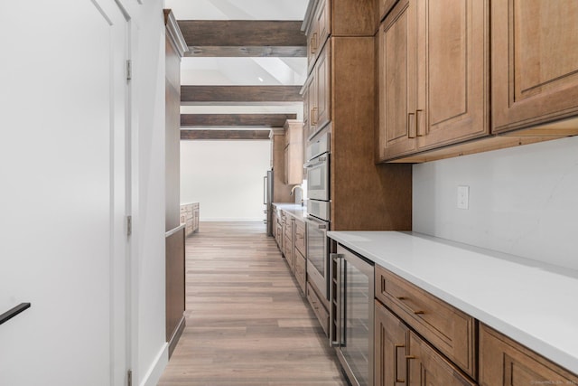 30 Tyrone Rd, Pomfret, CT 06259 - kitchen featuring beverage cooler, light countertops, light wood-style floors, beam ceiling, and brown cabinetry