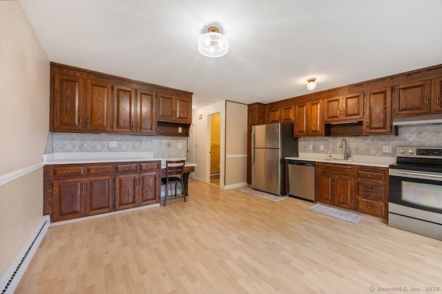 241 Judith Ln Unit 2, Waterbury, CT 06704 - kitchen featuring stainless steel appliances, a baseboard heating unit, under cabinet range hood, decorative backsplash, and light wood-style floors