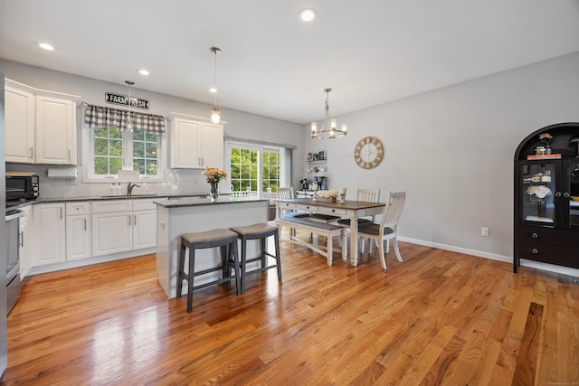 105 Hidden Pines Cir, Meriden, CT 06451 - kitchen with a kitchen island, dark countertops, white cabinets, a chandelier, and tasteful backsplash
