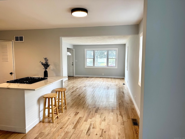 179 Mcgrath Ct, Stratford, CT 06615 - interior space with black gas stovetop, light wood-type flooring, a kitchen bar, light stone countertops, and a peninsula