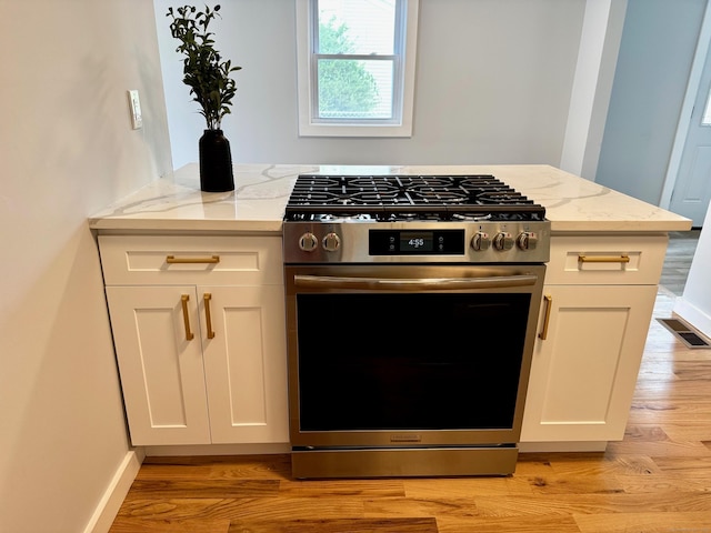 179 Mcgrath Ct, Stratford, CT 06615 - kitchen with stainless steel range with gas cooktop, light stone counters, light wood-style flooring, and white cabinets