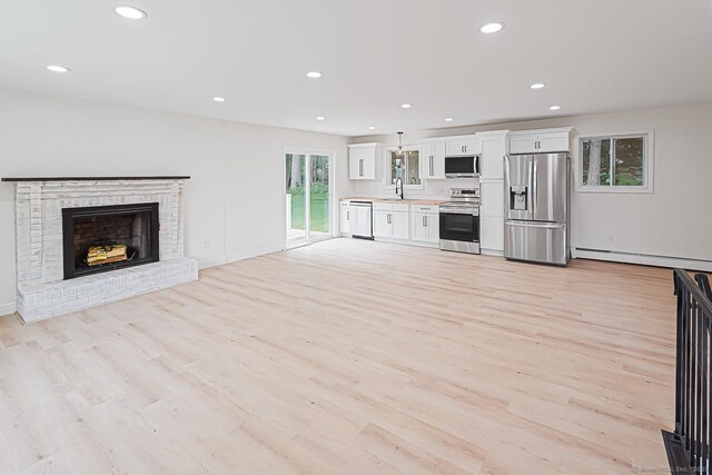 471 Moosup Pond Rd, Plainfield, CT 06354 - unfurnished living room featuring a baseboard radiator, recessed lighting, light wood-style flooring, and a brick fireplace