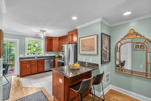 41 Palmer St Unit 20, Norwich, CT 06360 - kitchen with appliances with stainless steel finishes, a peninsula, ornamental molding, dark stone counters, and light wood-type flooring