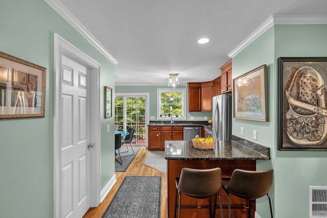 41 Palmer St Unit 20, Norwich, CT 06360 - kitchen with stainless steel appliances, crown molding, a peninsula, dark stone counters, and a breakfast bar