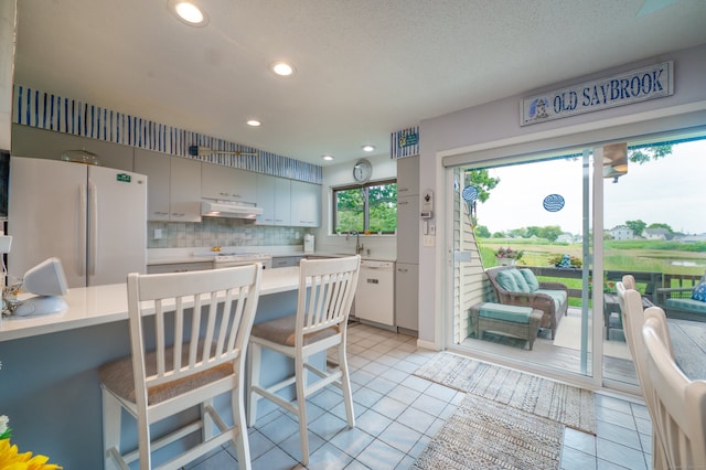 143 Sandy Point Rd Unit 143, Old Saybrook, CT 06475 - kitchen featuring white appliances, under cabinet range hood, light countertops, recessed lighting, and light tile patterned floors