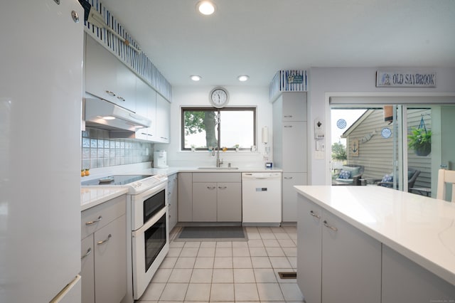 143 Sandy Point Rd Unit 143, Old Saybrook, CT 06475 - kitchen with white appliances, under cabinet range hood, light countertops, light tile patterned floors, and decorative backsplash