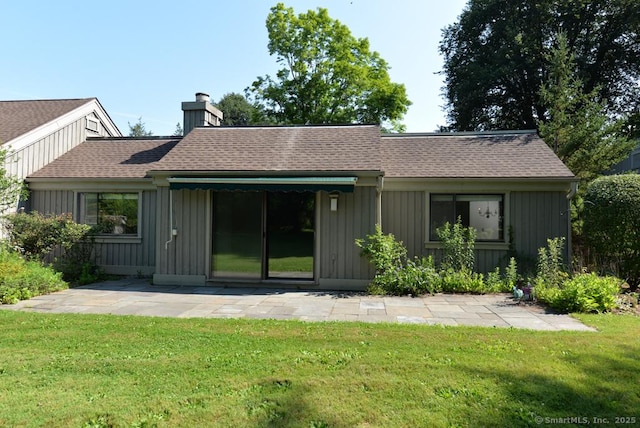 648 Heritage Vlg Unit A, Southbury, CT 06488 - rear view of property featuring a lawn, board and batten siding, roof with shingles, a chimney, and a patio area