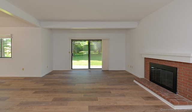 648 Heritage Vlg Unit A, Southbury, CT 06488 - unfurnished living room featuring plenty of natural light, a brick fireplace, and wood finished floors