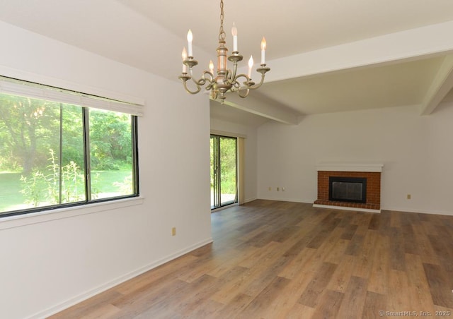 648 Heritage Vlg Unit A, Southbury, CT 06488 - unfurnished living room featuring healthy amount of natural light, a chandelier, wood finished floors, and a brick fireplace