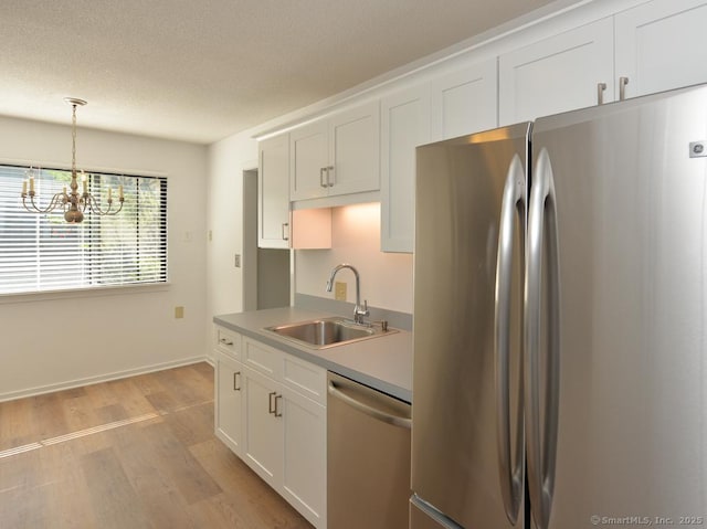648 Heritage Vlg Unit A, Southbury, CT 06488 - kitchen with stainless steel appliances, light wood-type flooring, a chandelier, white cabinetry, and pendant lighting