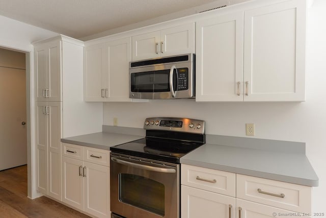 648 Heritage Vlg Unit A, Southbury, CT 06488 - kitchen with stainless steel appliances, light wood-style flooring, white cabinets, and light countertops