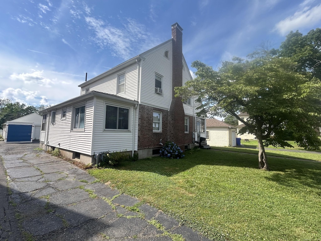 21 Walter Pl, East Hartford, CT 06108 - view of home's exterior featuring a lawn, an outbuilding, a chimney, a detached garage, and brick siding