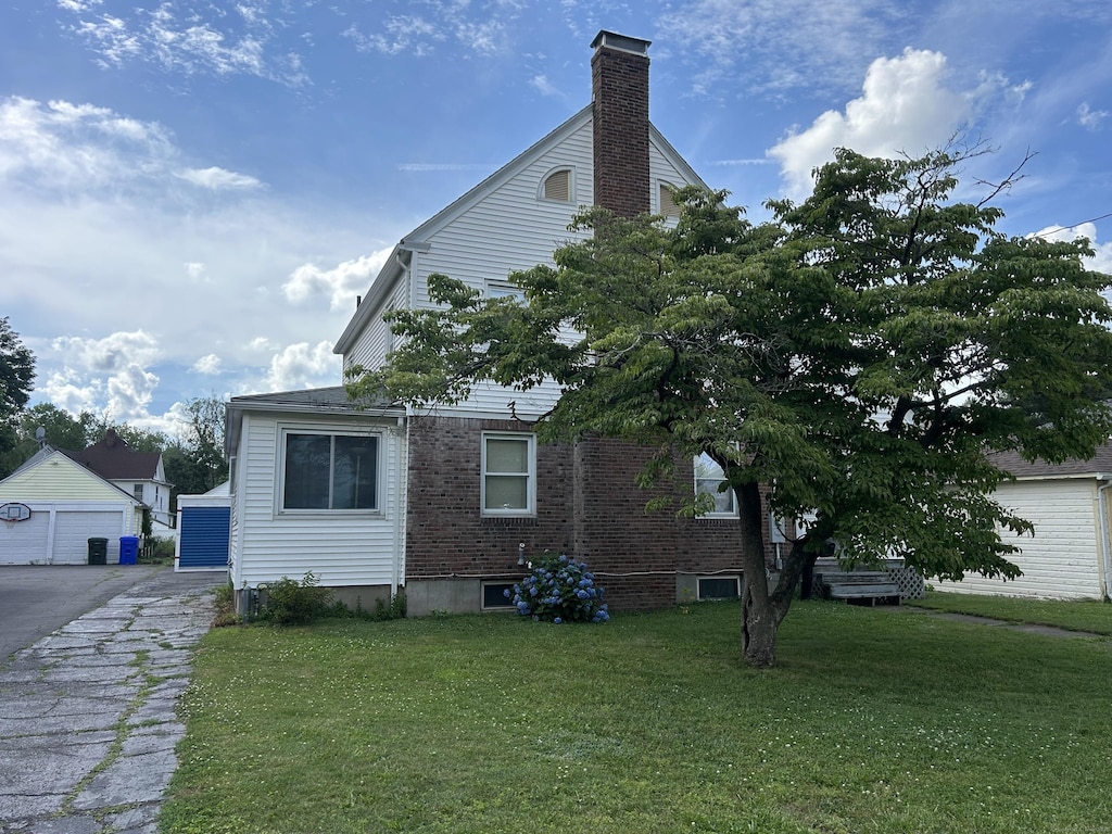 21 Walter Pl, East Hartford, CT 06108 - view of property exterior featuring brick siding, a yard, a chimney, and a detached garage
