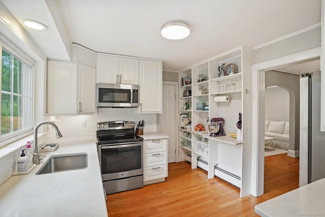 8 Gillies Ln, Norwalk, CT 06854 - kitchen featuring stainless steel appliances, arched walkways, light countertops, white cabinets, and crown molding