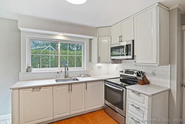 8 Gillies Ln, Norwalk, CT 06854 - kitchen featuring stainless steel appliances, decorative backsplash, light countertops, light wood finished floors, and white cabinetry