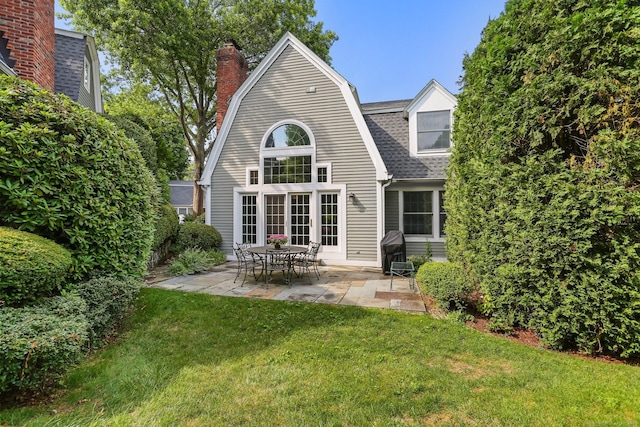 21 Lakeview Ave Unit 21, New Canaan, CT 06840 - back of property featuring a patio, a gambrel roof, a lawn, roof with shingles, and a chimney