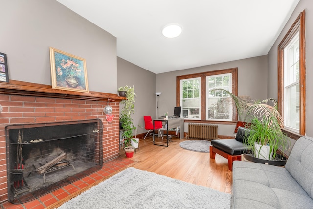 27 Thornton St, Hamden, CT 06517 - living room featuring radiator heating unit, wood finished floors, a brick fireplace, and an office area