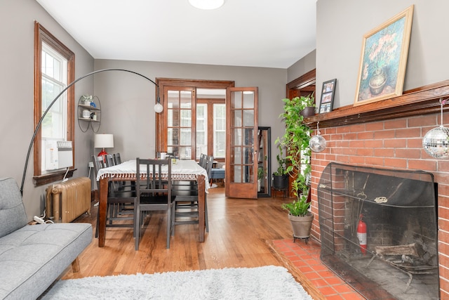 27 Thornton St, Hamden, CT 06517 - dining area with radiator heating unit, wood finished floors, a brick fireplace, cooling unit, and french doors