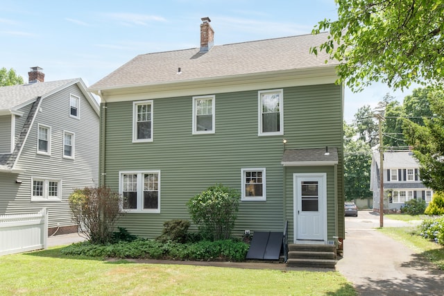 27 Thornton St, Hamden, CT 06517 - back of property with entry steps, a chimney, a yard, and roof with shingles