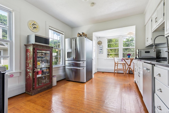 24 Warren Ave, Groton, CT 06355 - kitchen featuring appliances with stainless steel finishes, white cabinets, light wood finished floors, and dark countertops