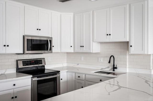 104 N St Apt 803, Stamford, CT 06902 - kitchen with stainless steel appliances, white cabinetry, backsplash, and light stone counters