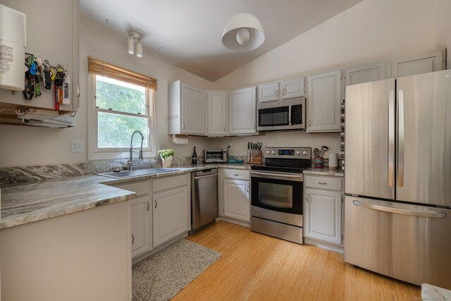 111 Nicole Dr, Milford, CT 06460 - kitchen with stainless steel appliances, light wood-style flooring, vaulted ceiling, and white cabinetry