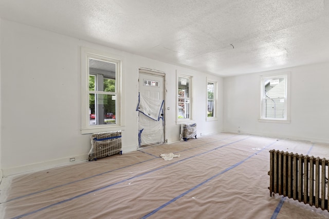 110 Franklin St, Killingly, CT 06239 - unfurnished living room with radiator, a textured ceiling, and healthy amount of natural light