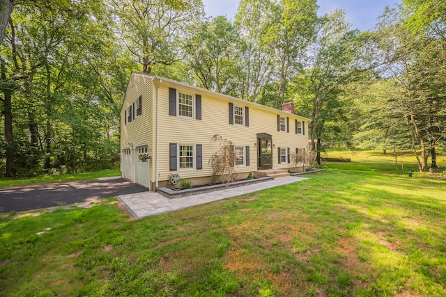 51 Brentley Dr, Shelton, CT 06484 - view of front of house with a chimney, driveway, a front lawn, an attached garage, and view of wooded area