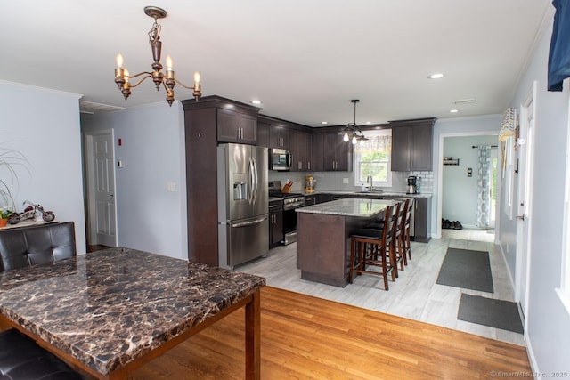 24 Dogwood Ln, Shelton, CT 06484 - kitchen with appliances with stainless steel finishes, a center island, a chandelier, ornamental molding, and a kitchen bar