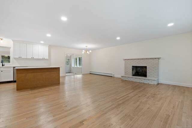 95 Great Ring Rd, Newtown, CT 06482 - unfurnished living room featuring a baseboard radiator, a chandelier, light wood-style floors, a brick fireplace, and recessed lighting