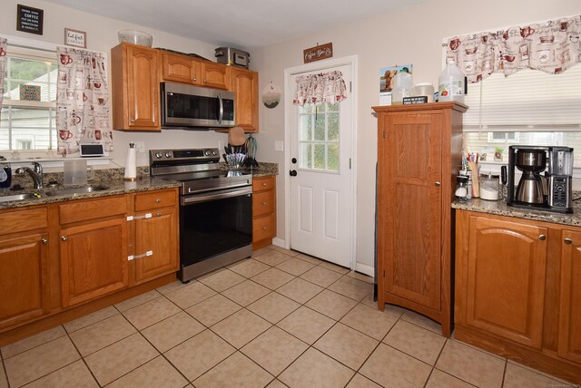 30 Foxcroft Dr, Manchester, CT 06040 - kitchen with stainless steel appliances, brown cabinetry, light tile patterned floors, and dark stone countertops