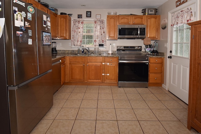 30 Foxcroft Dr, Manchester, CT 06040 - kitchen featuring appliances with stainless steel finishes, dark stone countertops, brown cabinetry, and light tile patterned floors