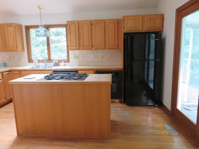 1200 Peck Ln, Cheshire, CT 06410 - kitchen with black appliances, a kitchen island, light wood finished floors, and tasteful backsplash