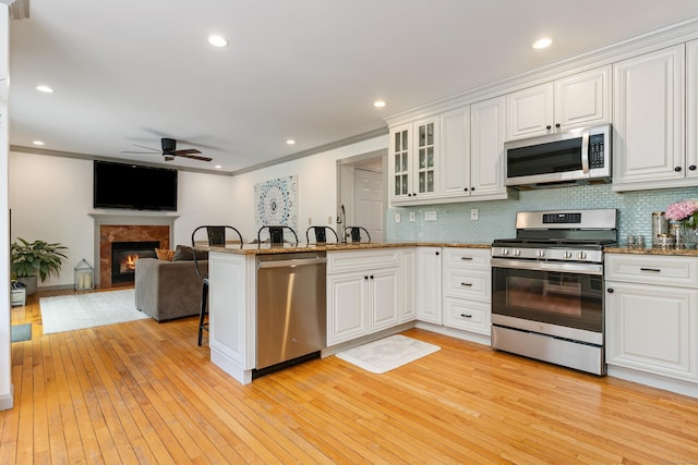 41 Arlington Rd, Stamford, CT 06902 - kitchen with appliances with stainless steel finishes, ceiling fan, a peninsula, white cabinetry, and light wood-type flooring