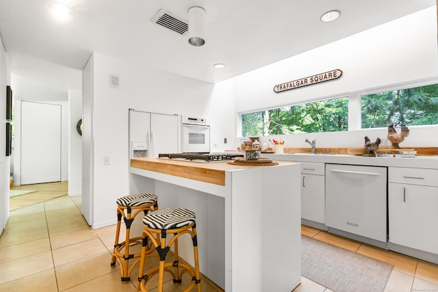 274 Nod Rd, Ridgefield, CT 06877 - kitchen with white appliances, light tile patterned floors, white cabinets, a kitchen breakfast bar, and recessed lighting