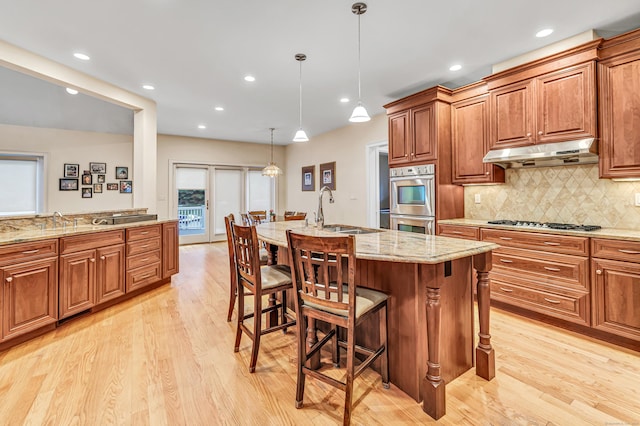 28 Aldo Dr, Woodbridge, CT 06525 - kitchen featuring under cabinet range hood, stainless steel appliances, light wood-type flooring, a breakfast bar, and light stone countertops