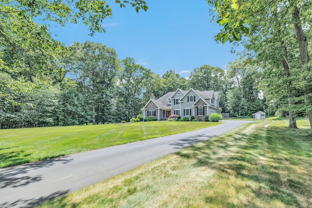 28 Aldo Dr, Woodbridge, CT 06525 - view of front facade with a storage unit, a front lawn, view of wooded area, driveway, and a chimney
