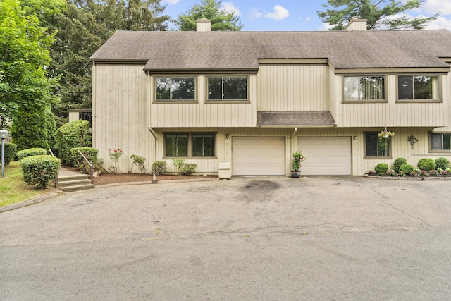 518 Iroquois Ln Unit A, Stratford, CT 06614 - view of property with a chimney, a shingled roof, asphalt driveway, and an attached garage