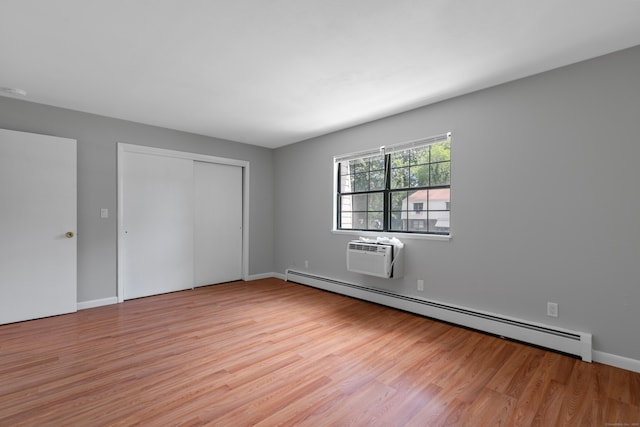 37 Enid St Apt C, Bridgeport, CT 06606 - unfurnished bedroom featuring a baseboard heating unit, light wood finished floors, a wall unit AC, and a closet