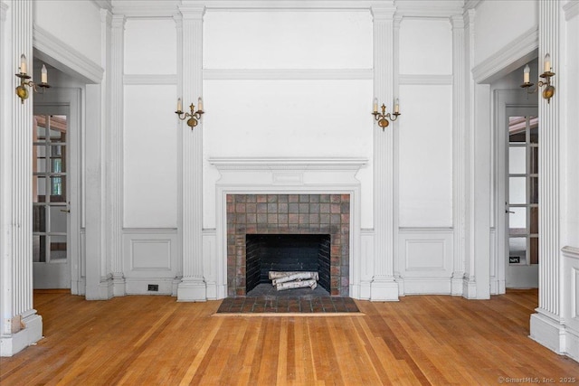 31 N Main St, Essex, CT 06426 - unfurnished living room featuring a decorative wall, wood finished floors, a fireplace, and ornate columns