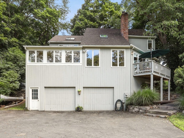 223 N St, Ridgefield, CT 06877 - rear view of property with a chimney, an attached garage, asphalt driveway, a shingled roof, and a deck
