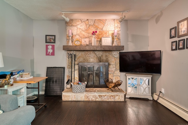 279 Annelise Ave, Southington, CT 06489 - living room with baseboard heating, rail lighting, a stone fireplace, hardwood / wood-style floors, and a textured ceiling