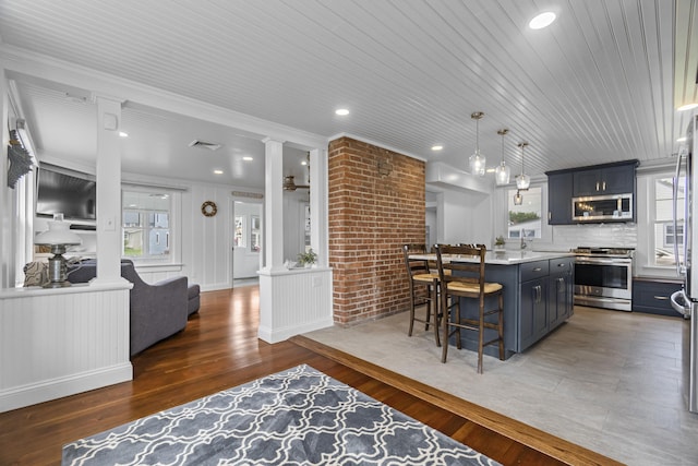 30 New Britain Rd, Old Lyme, CT 06371 - kitchen featuring appliances with stainless steel finishes, a breakfast bar, light countertops, a kitchen island, and wood finished floors