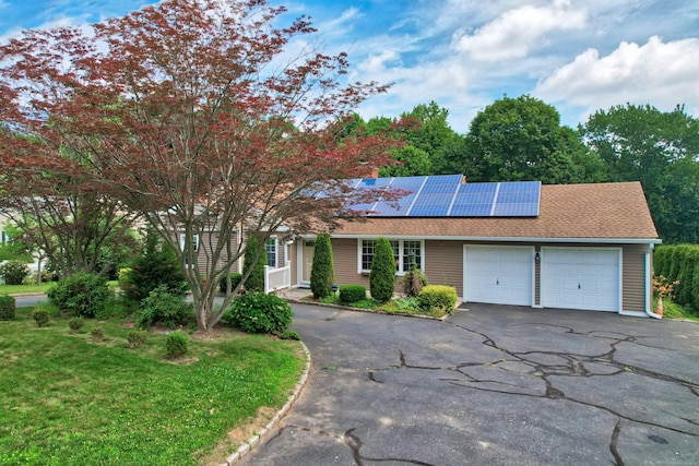 5338 Main St, Trumbull, CT 06611 - view of front facade with an attached garage, asphalt driveway, roof mounted solar panels, roof with shingles, and a front lawn