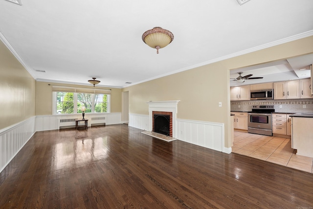 5338 Main St, Trumbull, CT 06611 - unfurnished living room with radiator heating unit, light wood-style floors, a brick fireplace, crown molding, and a wainscoted wall