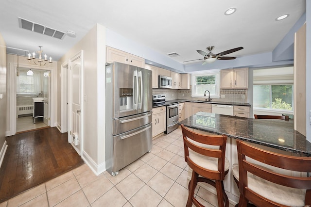 5338 Main St, Trumbull, CT 06611 - kitchen featuring appliances with stainless steel finishes, radiator heating unit, decorative backsplash, ceiling fan, and dark stone countertops